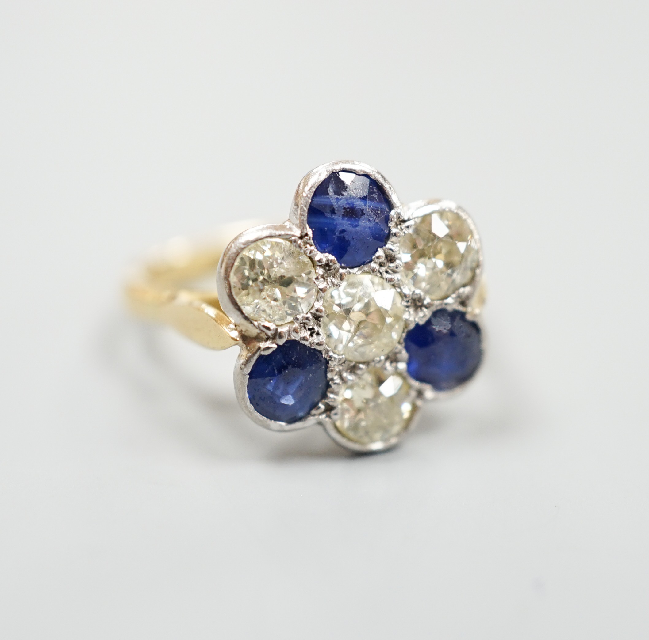 A modern 18ct gold, four stone diamond and three stone sapphire set flower head cluster ring, size J, gross weight 4.1 grams.